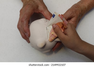 Hands Of An Older Woman Holding A Piggy Bank And Hand Of A Girl Depositing European Money