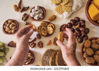 Hands Of An Older Woman Picking Up Nuts On A Table. Top View With Autumn Fruits.