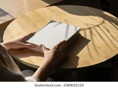 Hands on book mockup, lying on wooden table