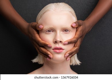 Hands on face. Grey-eyed woman with blonde bob cut having dark-skinned hands on face - Powered by Shutterstock