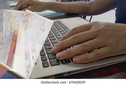 Hands on the keyboard, computer notebook .Handle euro money making business concept.