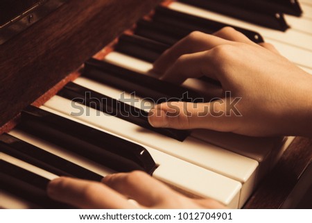 the hands on the piano keys. Photo piano in retro style.