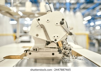 Hands on a sewing machine working in a textile factory industrial setting. Metal cotton sewing machine industry. Cotton sewing and fabrication textile industries. Metal hanger rails. - Powered by Shutterstock