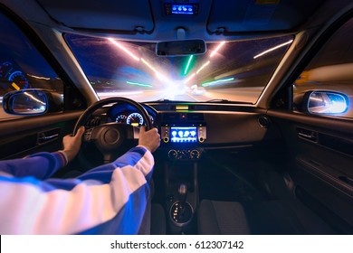 Hands On The Wheel A Car Moves At Fast Speed At The Night. Blured Road With Lights With Car On High Speed