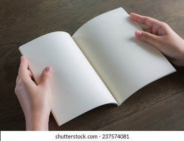 Hands open book on wood table