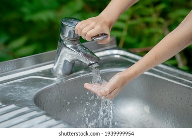 Hands Open For Drinking Tap Water. Pouring Fresh Healthy Drink. Good Habit. Right Choice. Child Washes His Hand Under The Faucet In The Garden. Environment And Health Care Concept. World Water Day