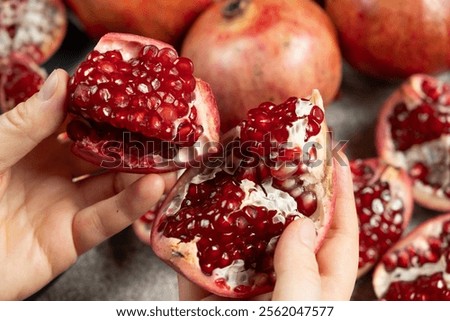 Hands open the pomegranate, separation into parts, pomegranates grains