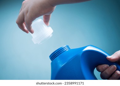 Hands opening blue liquid soap bottle on blue background  - Powered by Shutterstock