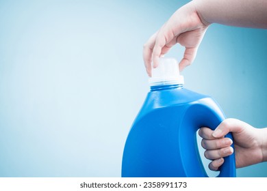 Hands opening blue liquid soap bottle on blue background  - Powered by Shutterstock