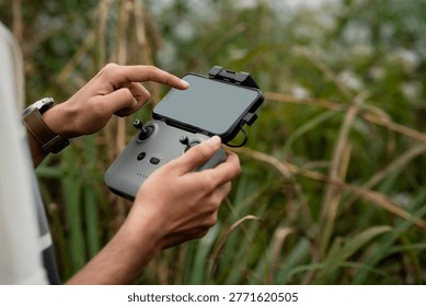 hands operating a drone remote controller outdoors in a natural environment, showcasing modern technology and aerial photography preparation
