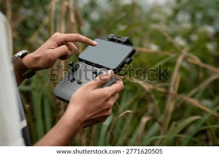 hands operating a drone remote controller outdoors in a natural environment, showcasing modern technology and aerial photography preparation