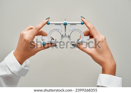 Hands of an ophthalmologist holding glasses used to test vision. Professional ophthalmological equipment in the clinic office.
