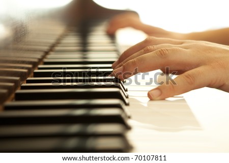 Hands over piano in warm tones.