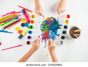 Hands Paint Brush. Kid Hands Painting At The Table With Art Supplies. Hands With Brush Painting With Watercolor Abstract Stains. Drawing On A White Sheet Of Paper. Creativity And Art.