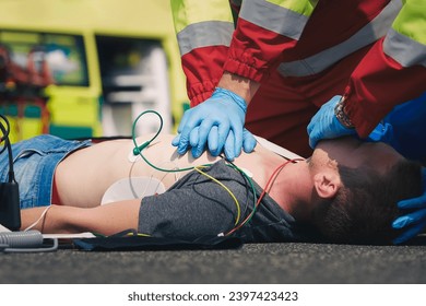 Hands of paramedic and doctor during resuscitation on road against ambulance car. Patient and team of emergency medical service. Themes rescue, urgency and health care.
 - Powered by Shutterstock