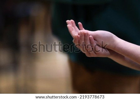 Hands of a parishioner clasped together about to recieve the host or bread from a priest at a cathlolic mass or communion liturgy or mass.