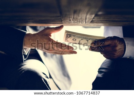 Hands passing money under table corruption bribery