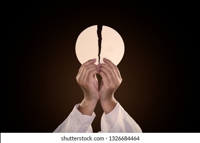 Hands of pastor splitting a communion bread in the dark background