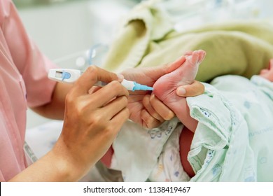 Hands Of Pediatric Nurse Holding And Using Accu-Chek Fastclix (needle Pen For Blood And Glucose Check) Stab On Sick Newborn Baby Foots To Prepare Check Glucose In His Blood At NICU Wards.