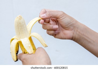 Hands peel the banana.