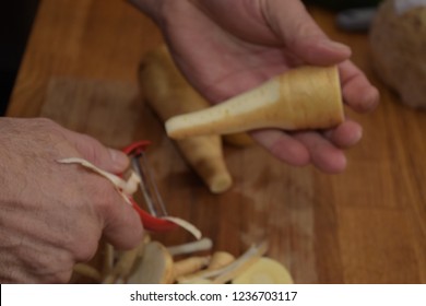 Hands peeling and chopping organic parsnip on a clean wooden  board  with a sharp knife  - Shutterstock ID 1236703117