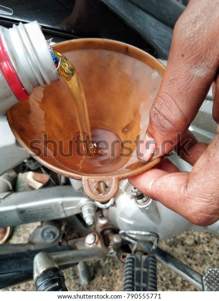 The hands of people filling the engine oil\
into the motorcycle