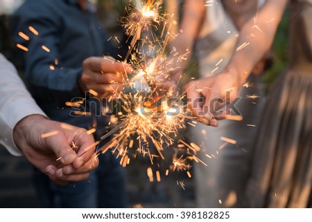 Hands of people holding Bengal light at the party