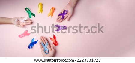 Hands of people holding colorful ribbons on pink background, cancer awareness, World cancer day, National cancer survivor day, world autism, supported living and illness, Prostate awareness concept.