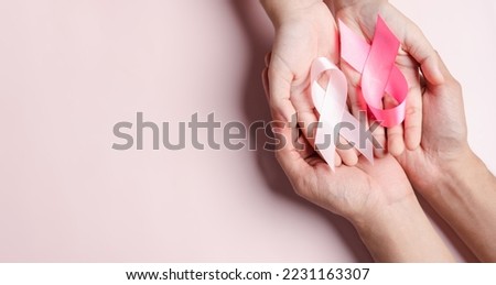 hands of people holding pink ribbons on pink background, Breast cancer awareness, world cancer day, national cancer survivor day in february concept.
