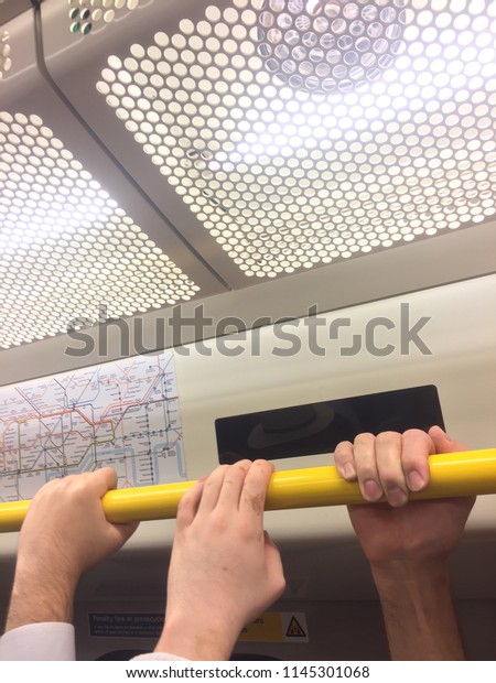 The hands of people holding a rail on a busy\
subway commute.
