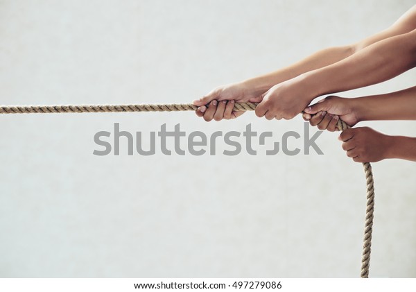 Hands of people pulling tug\
of war