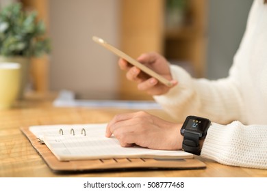 Hands Of Person Listening To Music On Smart Watch When Checking Phone