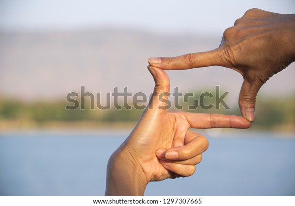 Hands of person making frame distance or symbol\
in nature.
