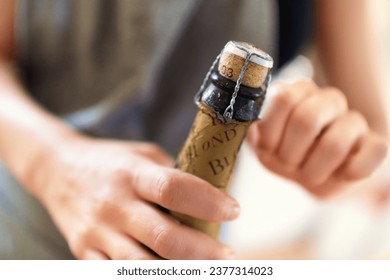 Hands, person and open cork on bottle of wine, champagne and alcohol for party, celebration and congratulations for special event. Closeup, drink and pop muselet, wire cage and cap of liquor beverage