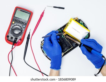 Hands of a person performing battery replacement in a portable game console on an isolated background. Concept of game console repair service. Top view. - Shutterstock ID 1836809089
