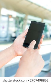 Hands of a person using a smartphone to interact with an app or website in a sunny outdoor setting