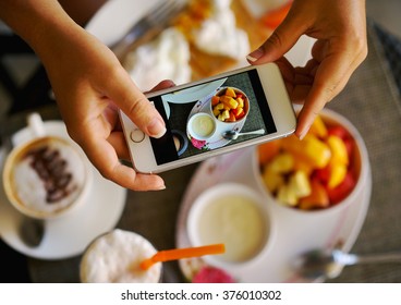 Hands with the phone close-up pictures of food. Breakfast for two : yogurt, coffee, fruit , toast. - Powered by Shutterstock