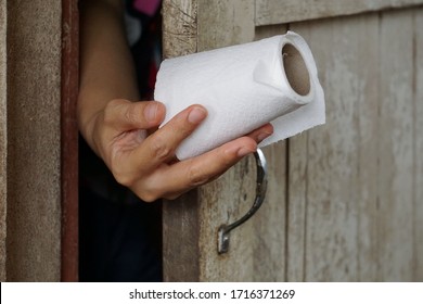 Hands Pick Up The Toilet Paper From Outside To Bring Back Into The Bathroom To Clean The Body.