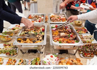 Hands picking up food from buffet catering table at the party.