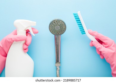 Hands in pink protective rubber gloves holding white plastic spray bottle and brush for shower head cleaning on light blue background. Pastel color. Limescale removing. Closeup. Point of view shot. - Powered by Shutterstock