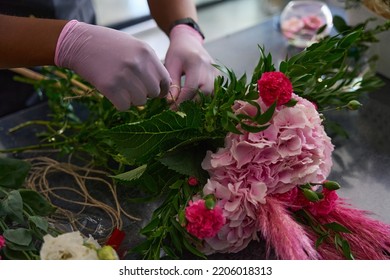 Hands in pink thick gloves wrap a bouquet - Shutterstock ID 2206018313
