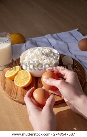 hands placing eggs on the table next to a bowl of cottage cheese	