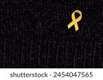 Hands placing a yellow ribbon pin on fabric, the international symbol of advocating for the return of hostages and raising awareness for cancer (specifically sarcoma) support and solidarity.