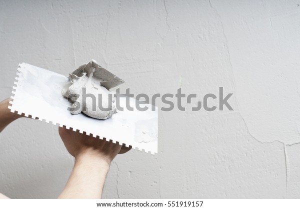 \
Hands Plasterer at work. Application of the\
plaster on the wall. textured\
plaster