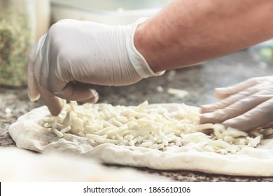 Hands With Plastic Gloves Of Pizza Chef Making Pizza At Kitchen