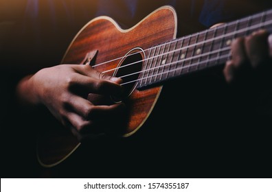 Hands playing acoustic guitar ukulele - Shutterstock ID 1574355187