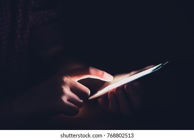 Hands are playing smartphones in dark rooms.
