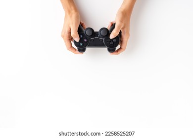 Woman’s hands playing video game controller over white background with copyspace. Top view - Shutterstock ID 2258525207