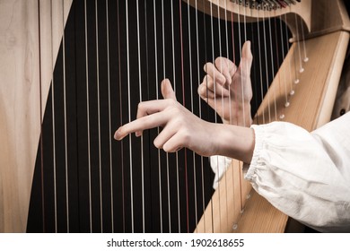 Hands playing wooden harp on black background