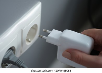 Hands plugging the charger into an outlet in the wall, close-up